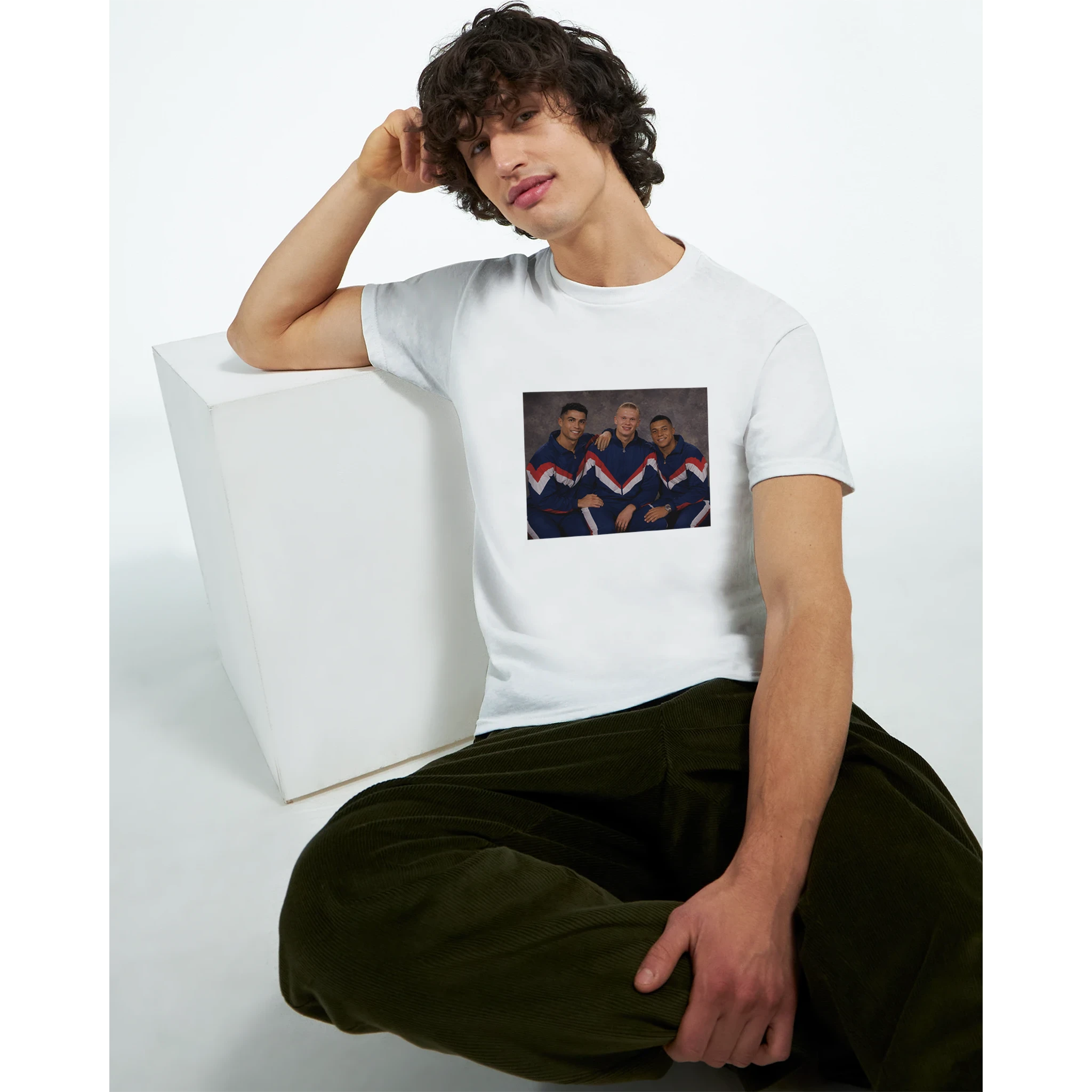 White crewneck T-shirt with retro soccer player graphic, worn by seated model.