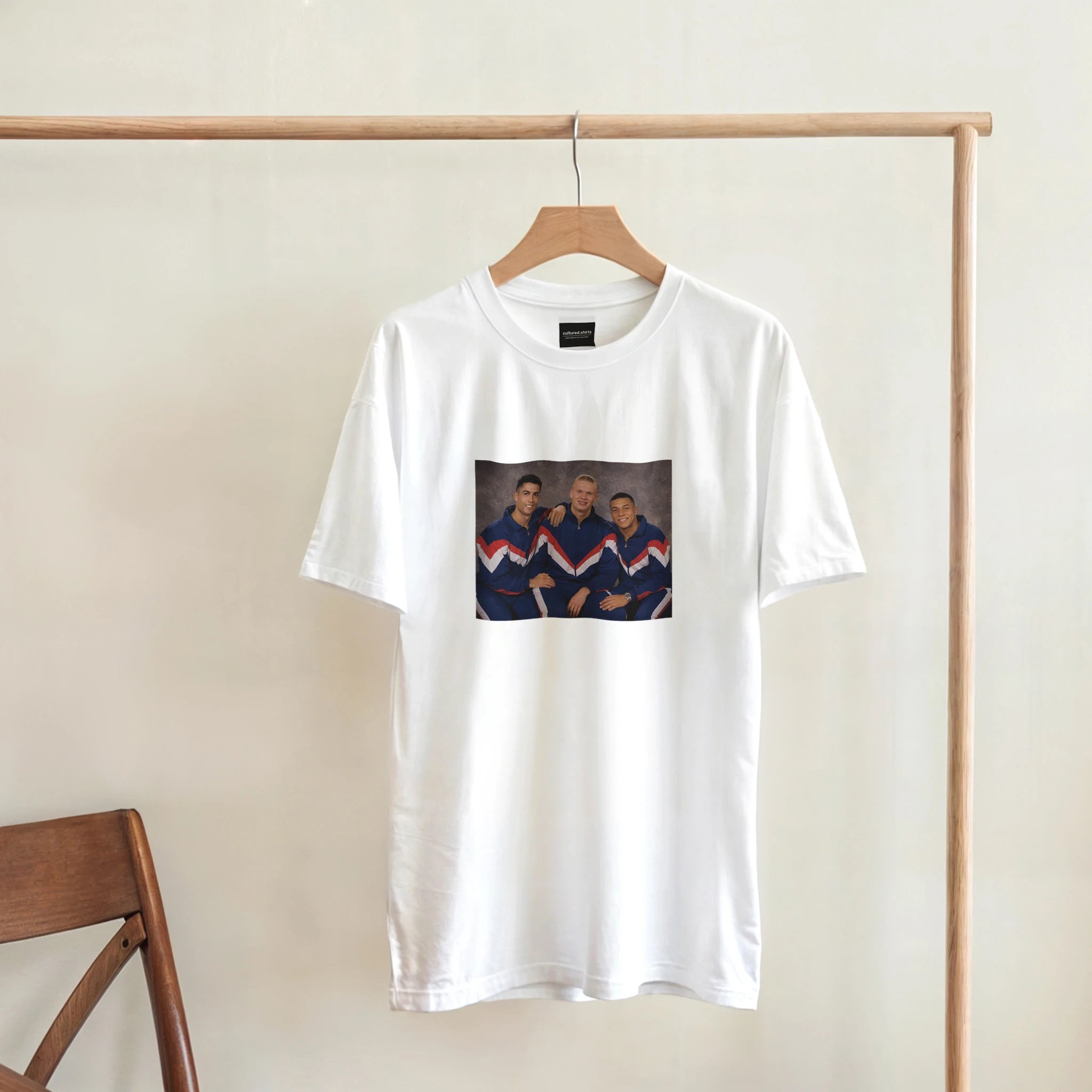 White crewneck T-shirt hanging on wooden hanger, retro soccer player graphic.